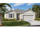 Charming single-story home with gray accents, manicured lawn, and an attached two-car garage, all under a sunny, blue sky at 1119 Olivine Ave, Dundee, FL 33838