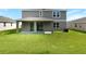 Backyard view reveals a modern two-story home with a covered patio and a well-maintained lawn at 1127 Olivine Ave, Dundee, FL 33838