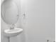 Bright half bathroom with a pedestal sink and round mirror at 1127 Olivine Ave, Dundee, FL 33838