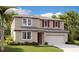 Two-story home boasts a manicured lawn, neutral siding, red shutters, and attached two car garage at 1127 Olivine Ave, Dundee, FL 33838