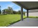 Covered patio view showcases a spacious backyard with lush green grass and mature trees at 1127 Olivine Ave, Dundee, FL 33838