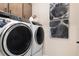 Laundry area with modern washer and dryer, complemented by decorative artwork on the wall and storage cabinets at 1139 Olivine Ave, Dundee, FL 33838