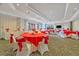 Bright event space featuring round tables with red tablecloths, white chairs with pink ribbons, and large windows at 1357 Venezia Ct # 302, Davenport, FL 33896