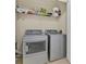 Convenient laundry room with modern washer and dryer, plus a wire shelf for storage at 1357 Venezia Ct # 302, Davenport, FL 33896