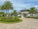 Inviting clubhouse with lush landscaping, palm trees, and a circular brick paved driveway at 1873 Flora Pass Pl, Kissimmee, FL 34747