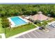 Aerial view of community pool featuring a clubhouse, playground, parking and manicured landscaping at 214 Farrington Ln, Kissimmee, FL 34744