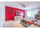 Bright bedroom featuring a red accent wall, ceiling fan, neutral carpet, and a light wood dresser at 214 Farrington Ln, Kissimmee, FL 34744