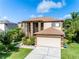 Charming two-story home featuring a well-manicured lawn, complemented by lush landscaping and a two-car garage at 214 Farrington Ln, Kissimmee, FL 34744