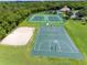 Community sand volleyball, basketball and tennis courts with green space, landscaping and a wooded area in the background at 214 Farrington Ln, Kissimmee, FL 34744