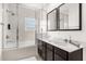 Bright bathroom with double sinks, dark cabinetry, and a soaking tub/shower with glass doors at 2634 Corvette Ln, Kissimmee, FL 34746
