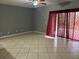 Neutral living room with tile floors, fan, and large window covered with patterned curtains at 2894 Tanzanite Ter, Kissimmee, FL 34758