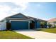 Attractive blue single-Gathering home featuring a well-kept lawn, palm trees, and a two-car garage at 318 Elderberry Ct, Kissimmee, FL 34759