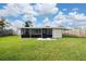 Spacious backyard featuring a covered porch with a concrete patio, lush green lawn, and wood fence at 403 Poinciana Cir, Kissimmee, FL 34744