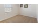 Empty bedroom with neutral carpet, window, and simple framed botanical art on the wall at 408 Danube Dr, Poinciana, FL 34759