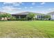 Home exterior highlighting the expansive backyard, lush green lawn, palm trees, and screened patio at 538 Via Vitale Ct, Kissimmee, FL 34759