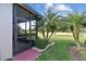 Exterior view of the screened patio overlooking the backyard with mature landscaping, small palms, and a lush green lawn at 538 Via Vitale Ct, Kissimmee, FL 34759