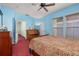 Bright bedroom featuring blue walls, a ceiling fan, two windows, and a comfortable bed with patterned bedding at 826 Lake Evalyn Dr, Celebration, FL 34747