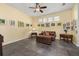 A living room with warm tan walls, artwork, ceiling fan, leather couch, and trunk coffee table at 826 Lake Evalyn Dr, Celebration, FL 34747