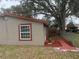 Side view of charming home with a well-maintained yard and a mature shade tree at 888 Berkley Rd, Auburndale, FL 33823