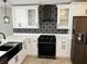 Modern kitchen features white cabinets, black stainless steel appliances, and decorative backsplash at 9319 Se 173Rd Hyacinth St, The Villages, FL 32162