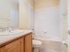 Bathroom featuring a wood vanity, a shower-tub combo, a neutral tile surround, and a toilet at 100 Ventana Dr, Kissimmee, FL 34759
