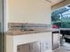 This outdoor kitchen features a stainless steel mini fridge, grill, sink, and ceramic tile backsplash at 100 Ventana Dr, Kissimmee, FL 34759
