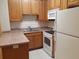 Kitchen with wooden cabinetry, double sink, and white appliances offering functionality at 1111 Oscar Sq, Celebration, FL 34747