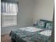 Bright bedroom with a patterned duvet cover, bedside table, and a sunny window with blinds at 1116 Caloosa Ridge Way, Babson Park, FL 33827