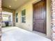 Inviting front porch with stone columns, a dark wood front door, and neutral exterior paint at 12880 Westside Village Loop, Windermere, FL 34786