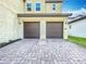 Close-up of the home's two-car garage with dark brown doors and a paver driveway at 12880 Westside Village Loop, Windermere, FL 34786