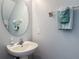 Half bath with a pedestal sink, round mirror, and fresh towels on a rack at 131 Stella Pass, Davenport, FL 33837