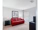 Bright bonus room with a red sofa, carpet flooring, and plenty of natural light at 131 Stella Pass, Davenport, FL 33837