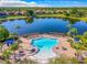 Aerial view of the community pool and lake with palm trees and lounge area at 131 Stella Pass, Davenport, FL 33837