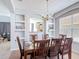 Formal dining room with a wooden table, chandelier, built-in shelving, and an open view to the living space at 131 Stella Pass, Davenport, FL 33837