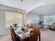 Formal dining room with wood table set for dinner and open floorplan to the adjacent living room at 131 Stella Pass, Davenport, FL 33837