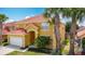 Charming two-story home with a yellow exterior, red tile roof, lush landscaping and a two-car garage at 131 Stella Pass, Davenport, FL 33837