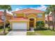 Two story home featuring an attached garage, terra cotta roof, and manicured lawn at 131 Stella Pass, Davenport, FL 33837