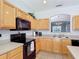 The kitchen features wooden cabinets, tile floors, and a view of the formal dining room at 131 Stella Pass, Davenport, FL 33837