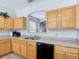 Bright kitchen boasts wooden cabinetry, a black dishwasher, and an open layout at 131 Stella Pass, Davenport, FL 33837