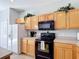Kitchen features wooden cabinets, black appliances and tile floors at 131 Stella Pass, Davenport, FL 33837