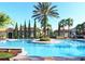 Resort-style community pool with a center island and sunbathing deck surrounded by palm trees at 1351 Tuscan Ter # 8408, Davenport, FL 33896