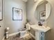 Charming powder room with a pedestal sink, round mirror, toilet, and decorative artwork, all in neutral tones at 16150 Parkwyn St, Winter Garden, FL 34787