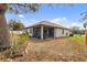 View of the backyard with brown grass, landscaping, and a screened lanai at 19331 Briercrest Trl, Orlando, FL 32833