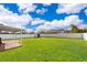 Expansive backyard with lush green grass, a white fence, a storage shed, and a covered patio area at 2286 Sunny St, Kissimmee, FL 34741
