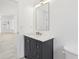 Stylish bathroom featuring a dark vanity, marble countertop, modern faucet, and sleek mirror at 411 Boxwood Dr, Davenport, FL 33837