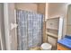 Compact bathroom features a toilet, cabinet storage, and shower with patterned curtain at 500 Monroe Cir, Davenport, FL 33896