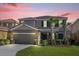 Charming two-story home featuring a tile roof, well-manicured lawn and two-car garage at sunset at 5117 Oakbourne Ave, Davenport, FL 33837