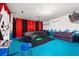 Finished basement game room with blue flooring, black leather sectional sofa, and movie projector at 5117 Oakbourne Ave, Davenport, FL 33837