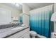A bathroom featuring tile flooring, a granite countertop, a large mirror, and a shower with an blue shower curtain at 5512 Solterra Cir, Davenport, FL 33837