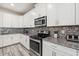 Well-equipped kitchen features stainless steel appliances, granite countertops, and white cabinets for a sleek design at 5512 Solterra Cir, Davenport, FL 33837